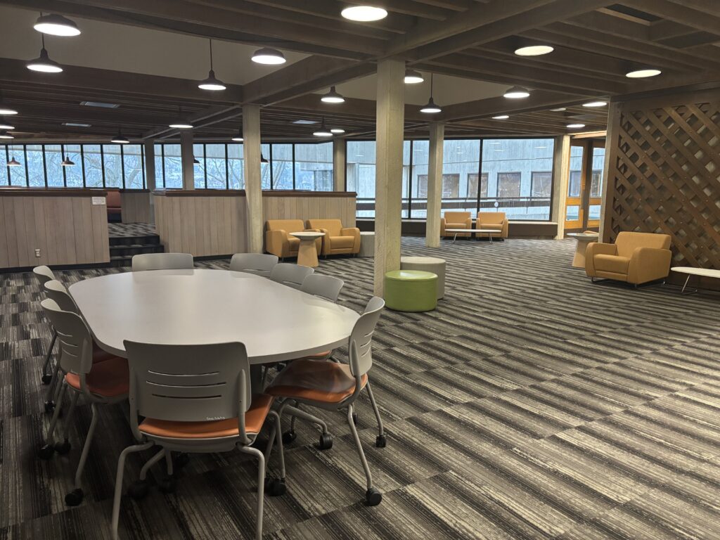 An open lobby area with lounge chairs and a table for group study on the 3rd floor of the South Campus Center.