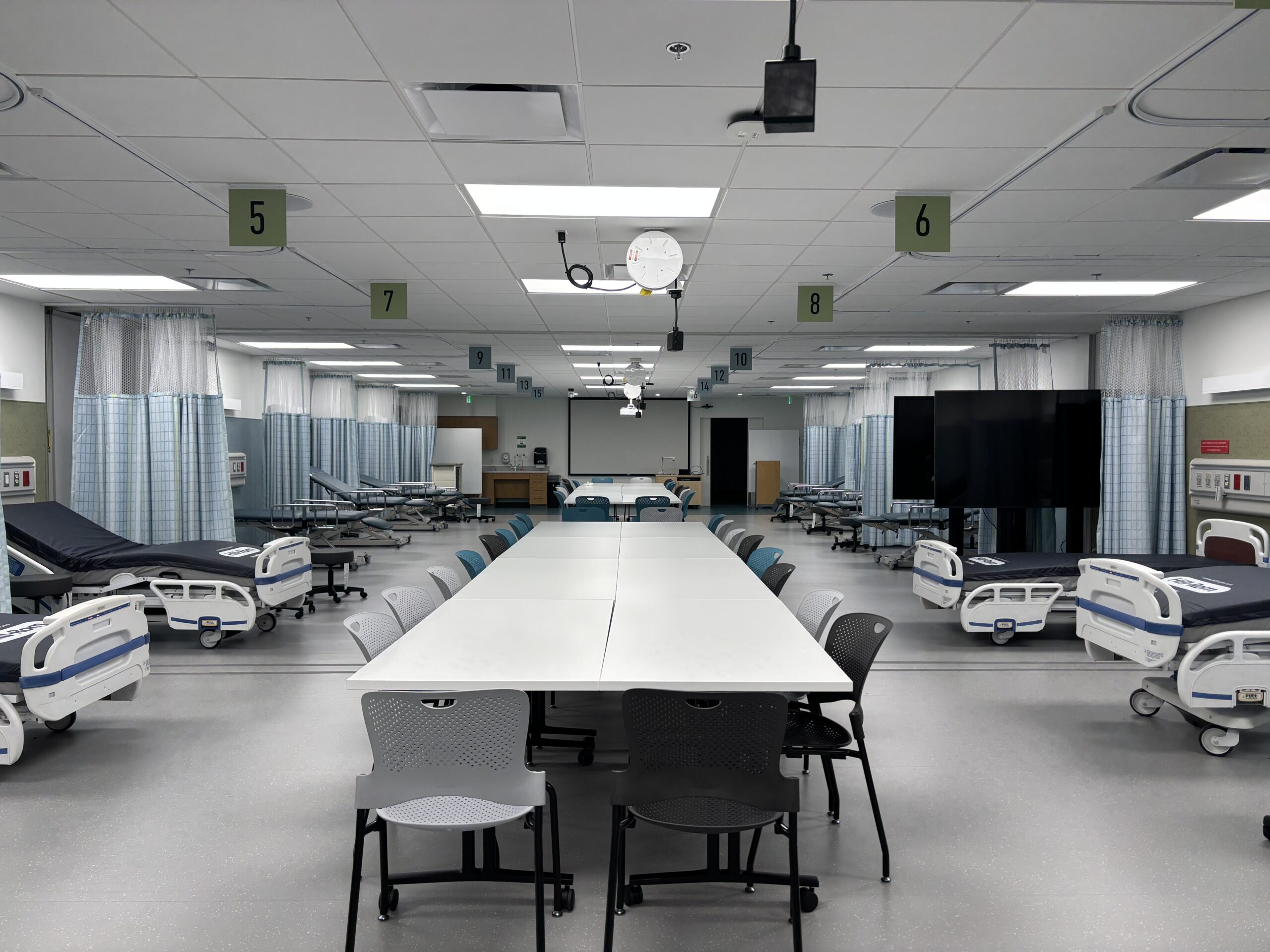Photo of the T674 and T675 clinical skills labs, showing the layout of exam and hospital beds, tables, and chairs.